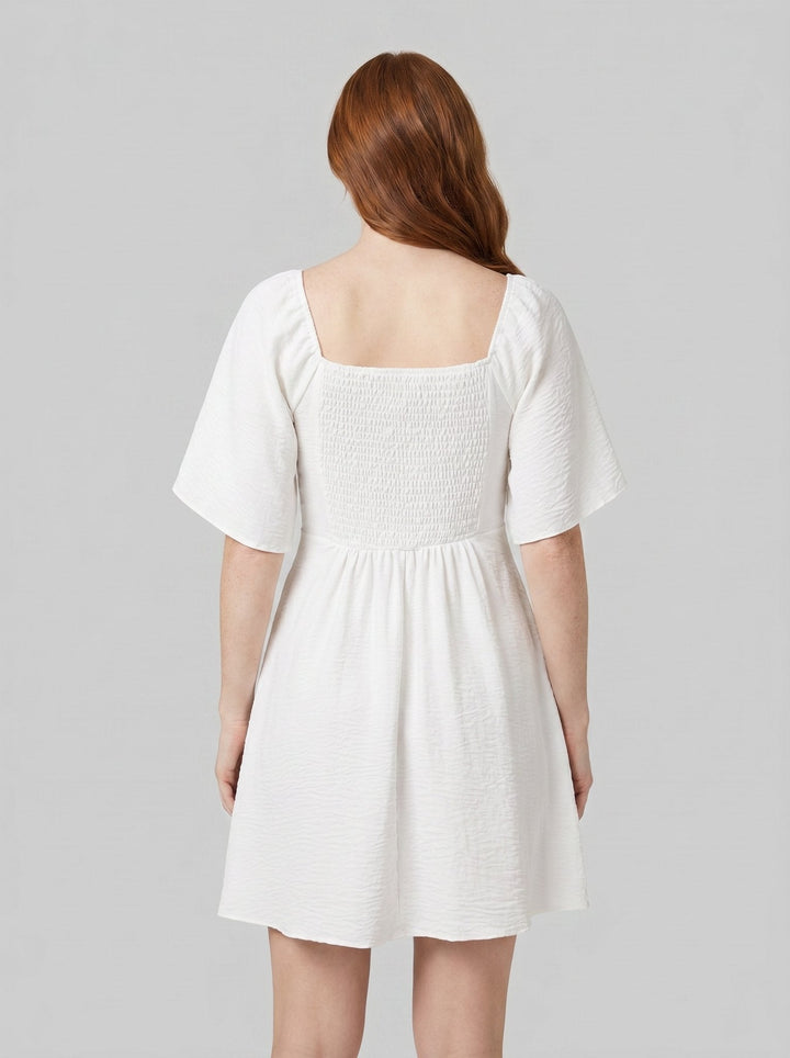 Charline mini dress in white, back view showing the smocked bodice