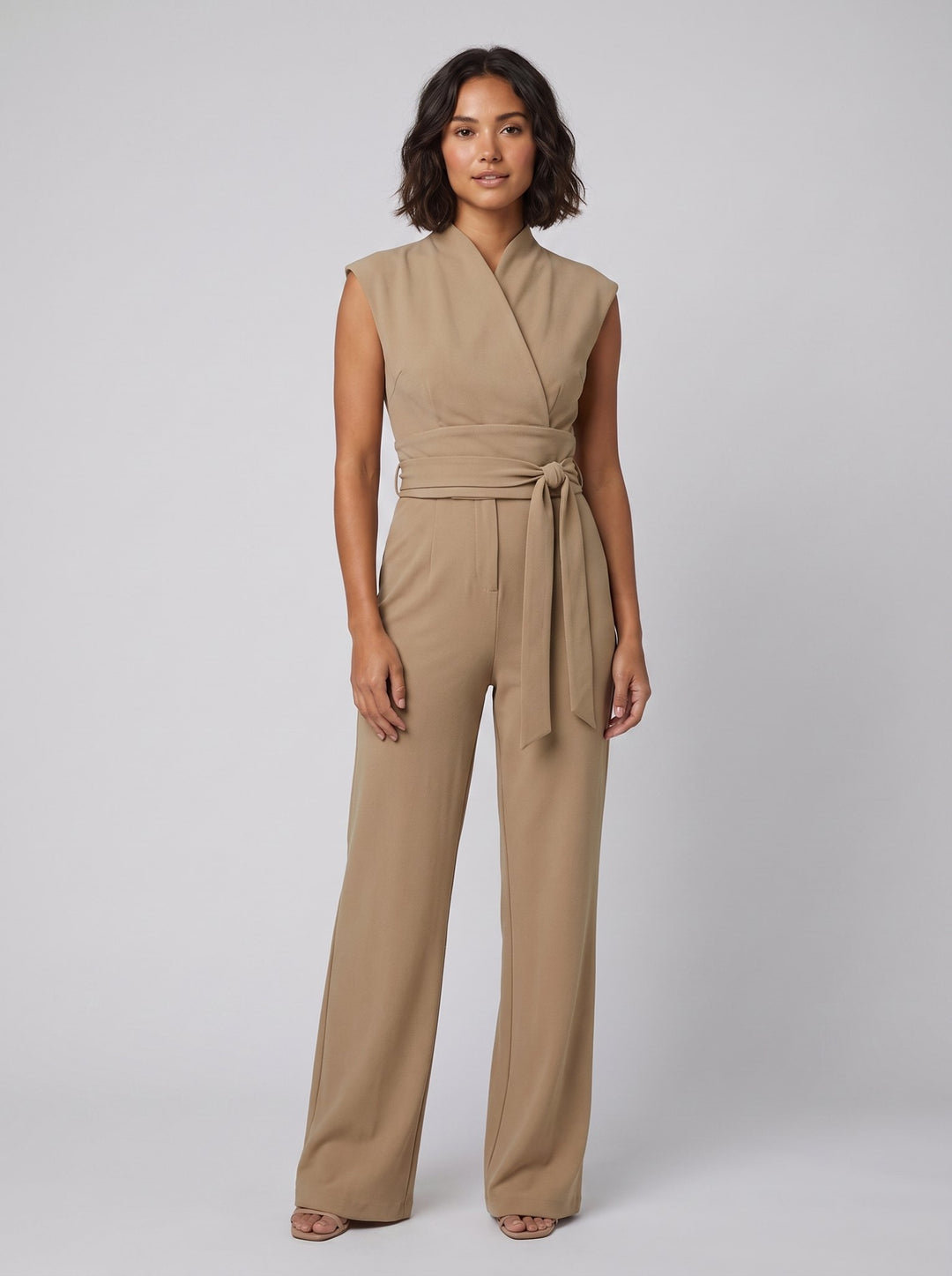 Malin Tassou chic sleeveless overall in khaki tan with wrap tie belt, front view on model